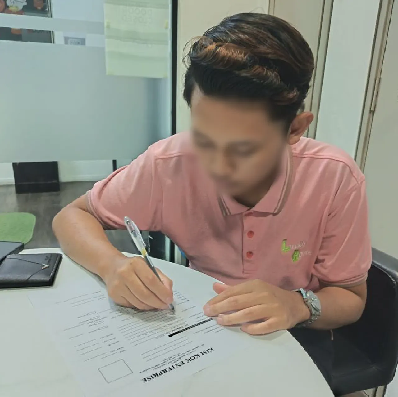 Peminjam menandatangani perjanjian di pejabat Kim Kok Enterprise; wajah dikabur untuk privasi.